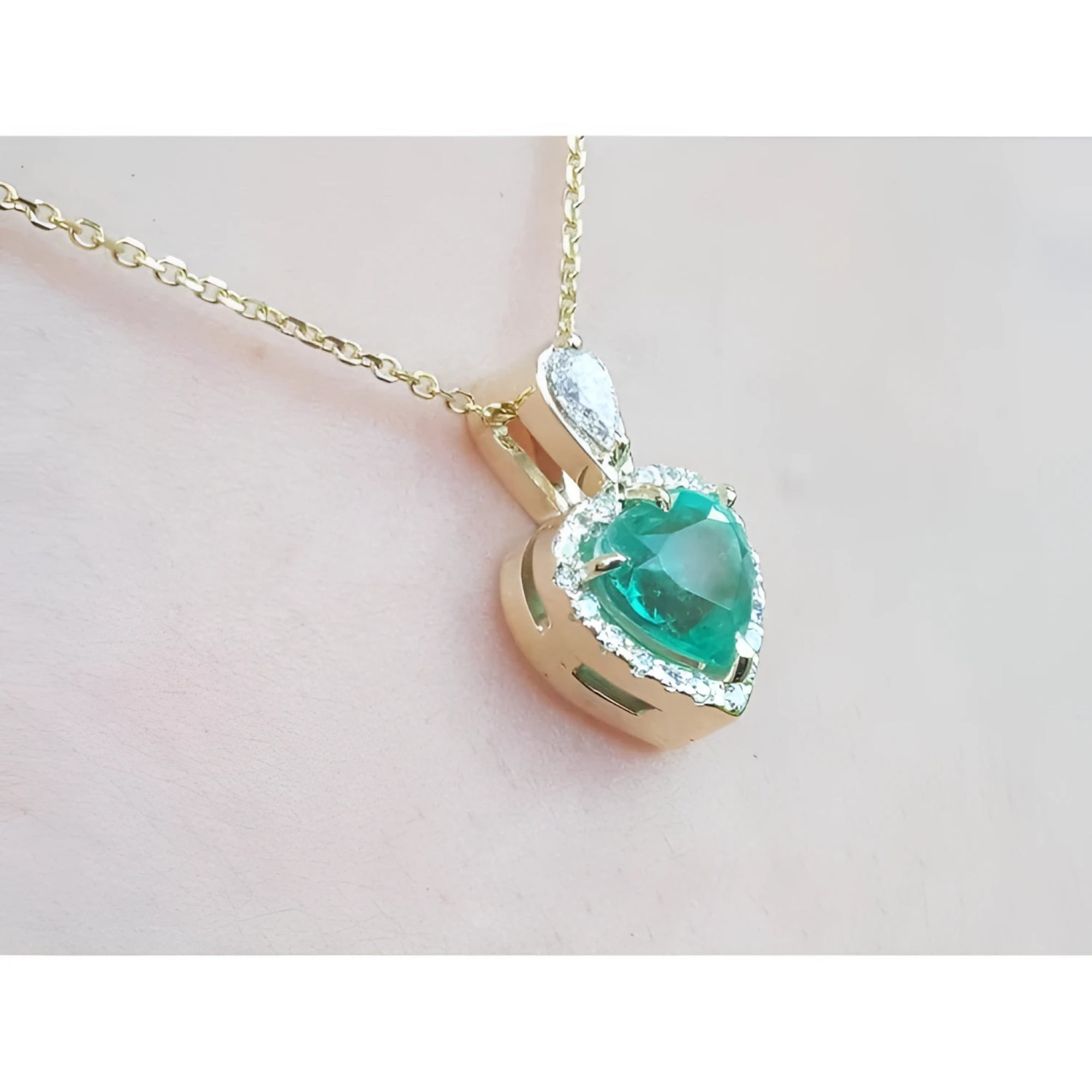 14K yellow gold heart pendant with a medium-deep green emerald and diamond halo on a delicate chain.