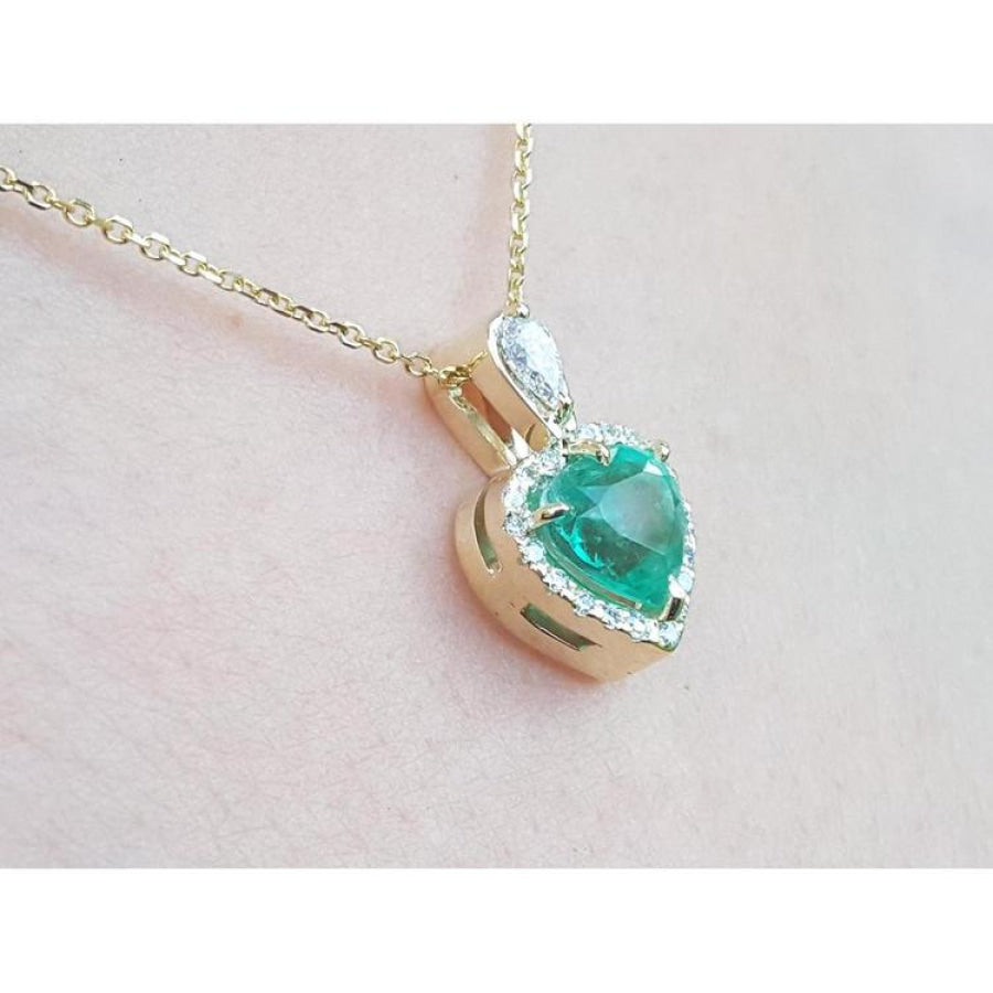 14K yellow gold heart pendant with a medium-deep green emerald and diamond halo on a delicate chain.