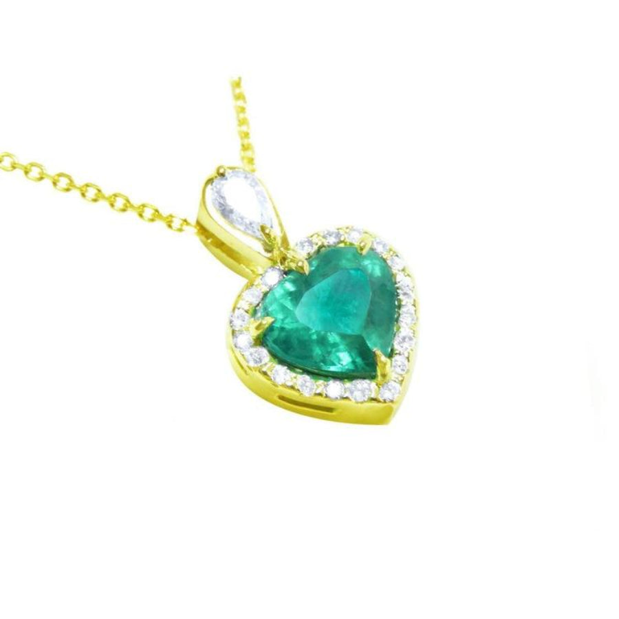Heart-shaped emerald pendant with gold frame and halo of natural diamond accents. 