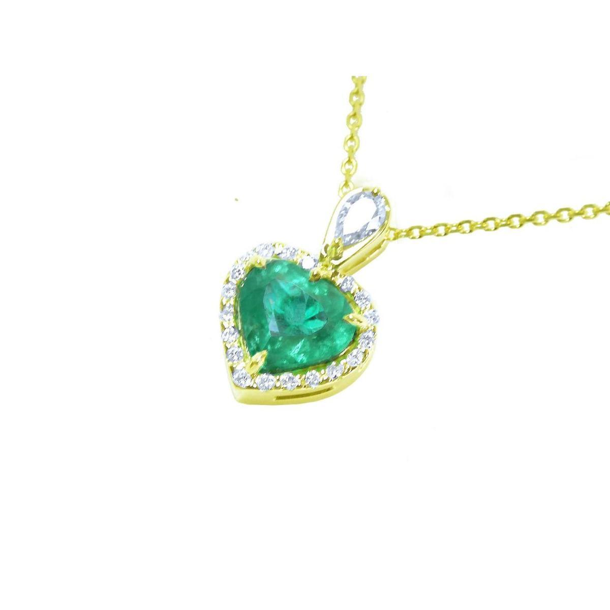 Gold pendant with a heart-shaped emerald and halo diamonds on a white background.