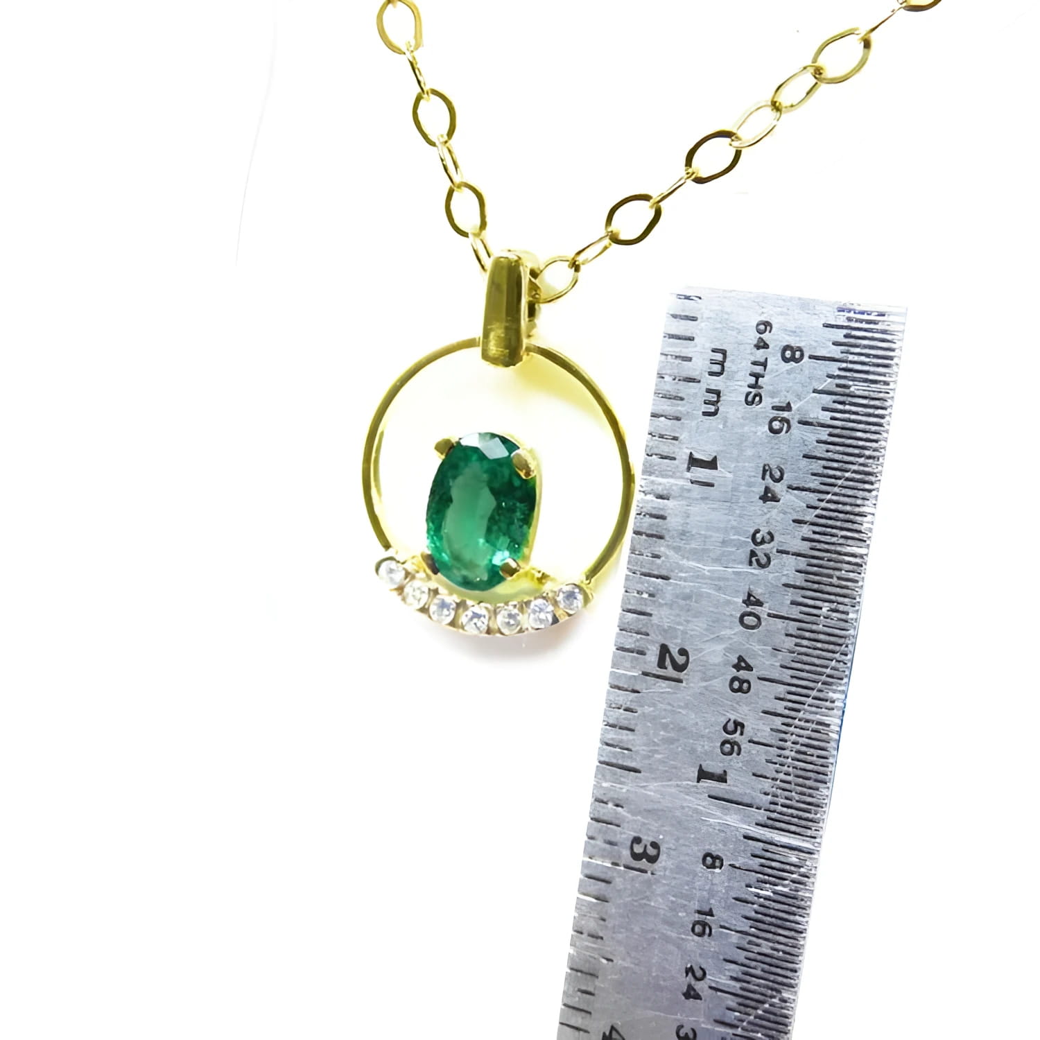 14k yellow gold necklace with oval 0.85 ct Colombian emerald and diamond accents, shown with ruler for scale.