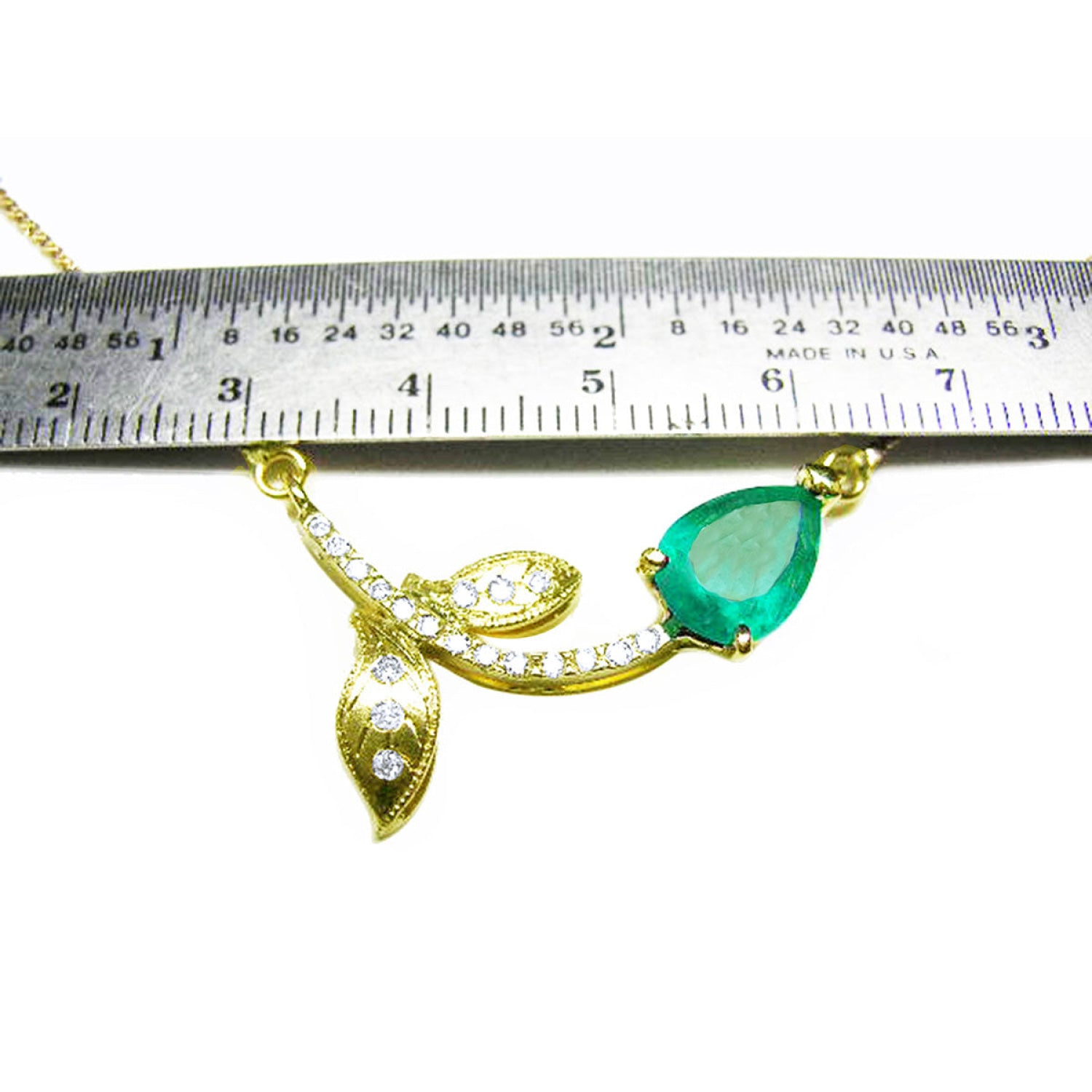 14K yellow gold twig necklace with a pear-cut Colombian emerald and diamond accents, measured by a ruler.