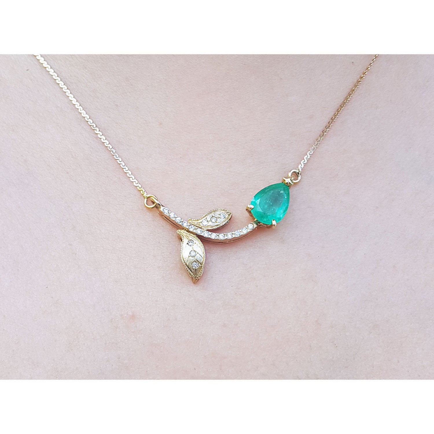 1.66 carat pear-cut natural emerald necklace in 14K yellow gold with diamond-accented twig design.