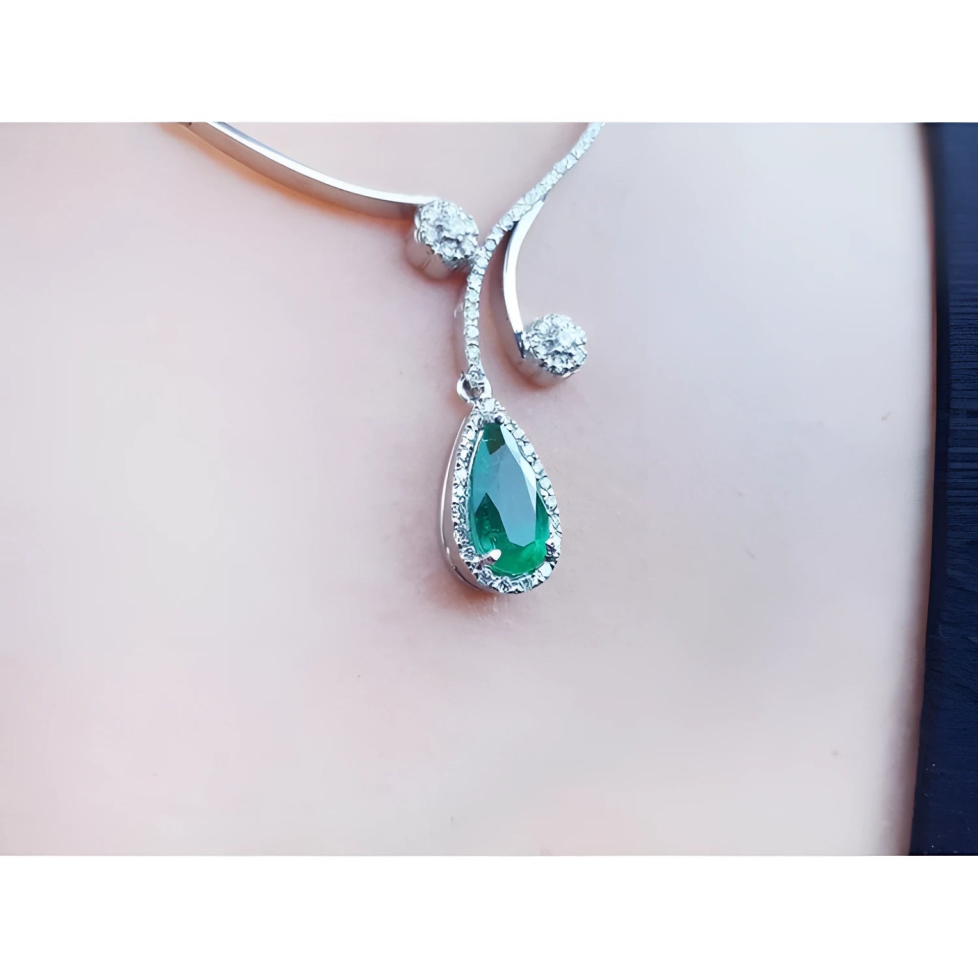 Pear cut 2.26ct natural emerald necklace in 18K white gold with diamond halo and accents.
