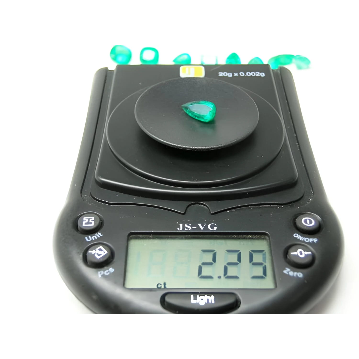2.25 ct. natural pear-cut Muzo mine Colombian emerald on a digital scale, displaying vivid bluish-green color.