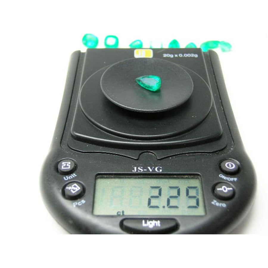 2.25 ct. natural pear-cut Muzo mine Colombian emerald on a digital scale, displaying vivid bluish-green color.