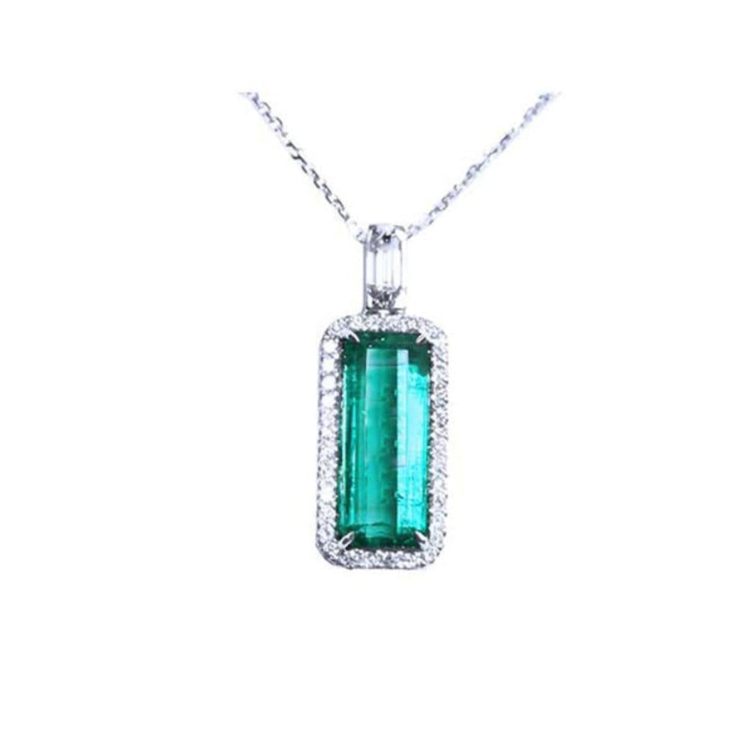 Elongated natural emerald pendant with halo diamonds on an 18K white gold chain.