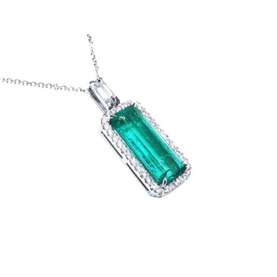 Elongated natural emerald pendant with halo diamonds in 18K white gold.