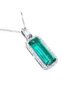 Elongated natural emerald pendant with halo diamonds in 18K white gold.