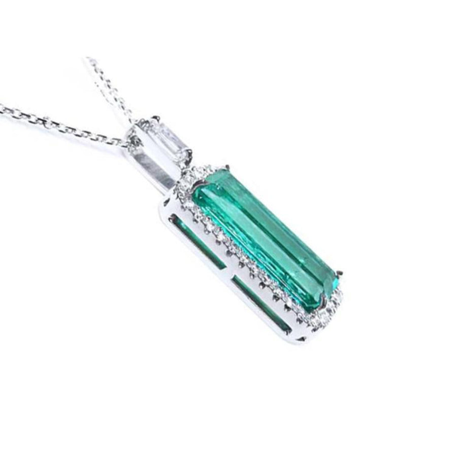 An elongated emerald pendant with side galley view, halo diamonds in 18k white gold.