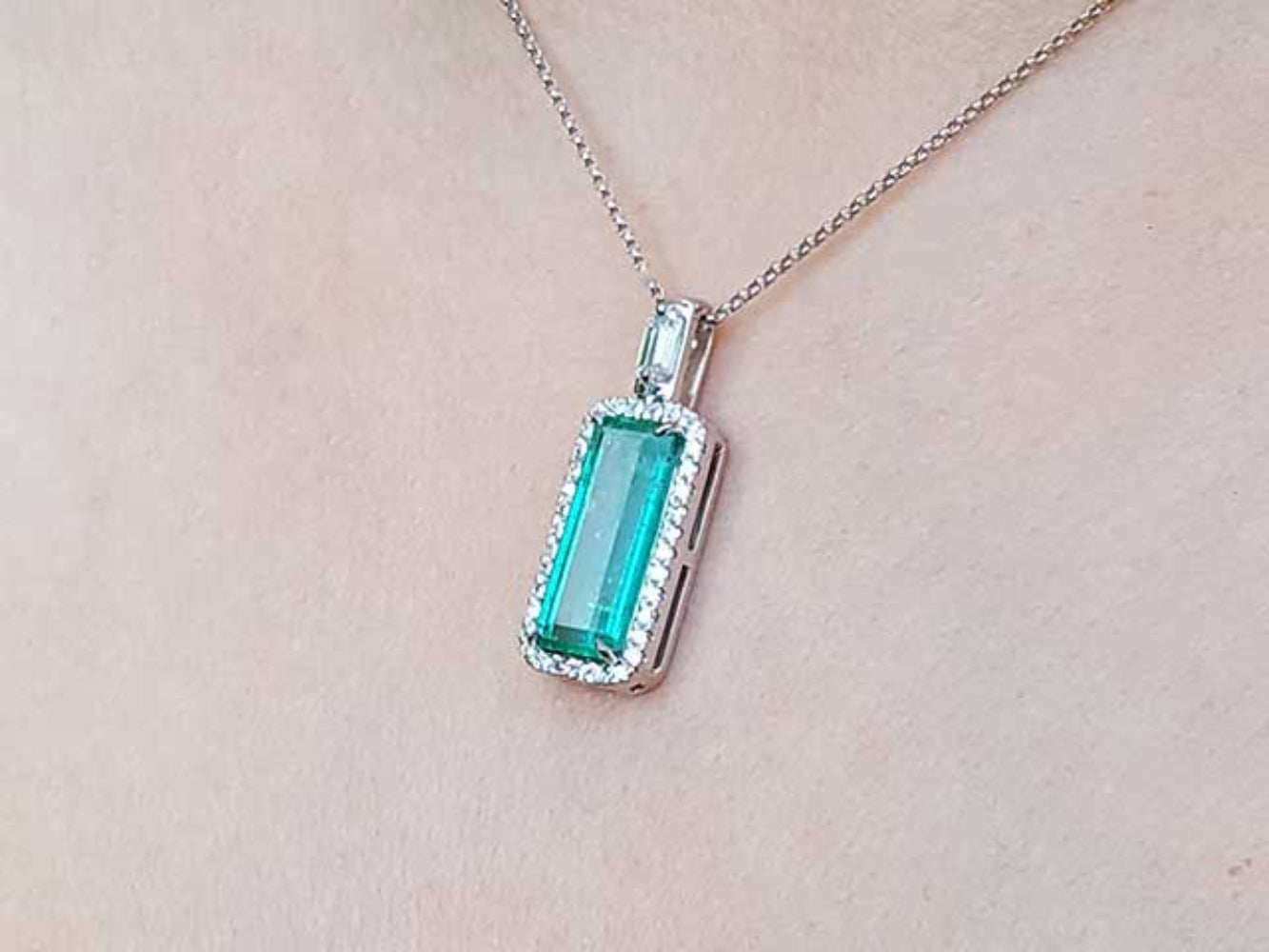 Emerald pendant necklace on a light skin background