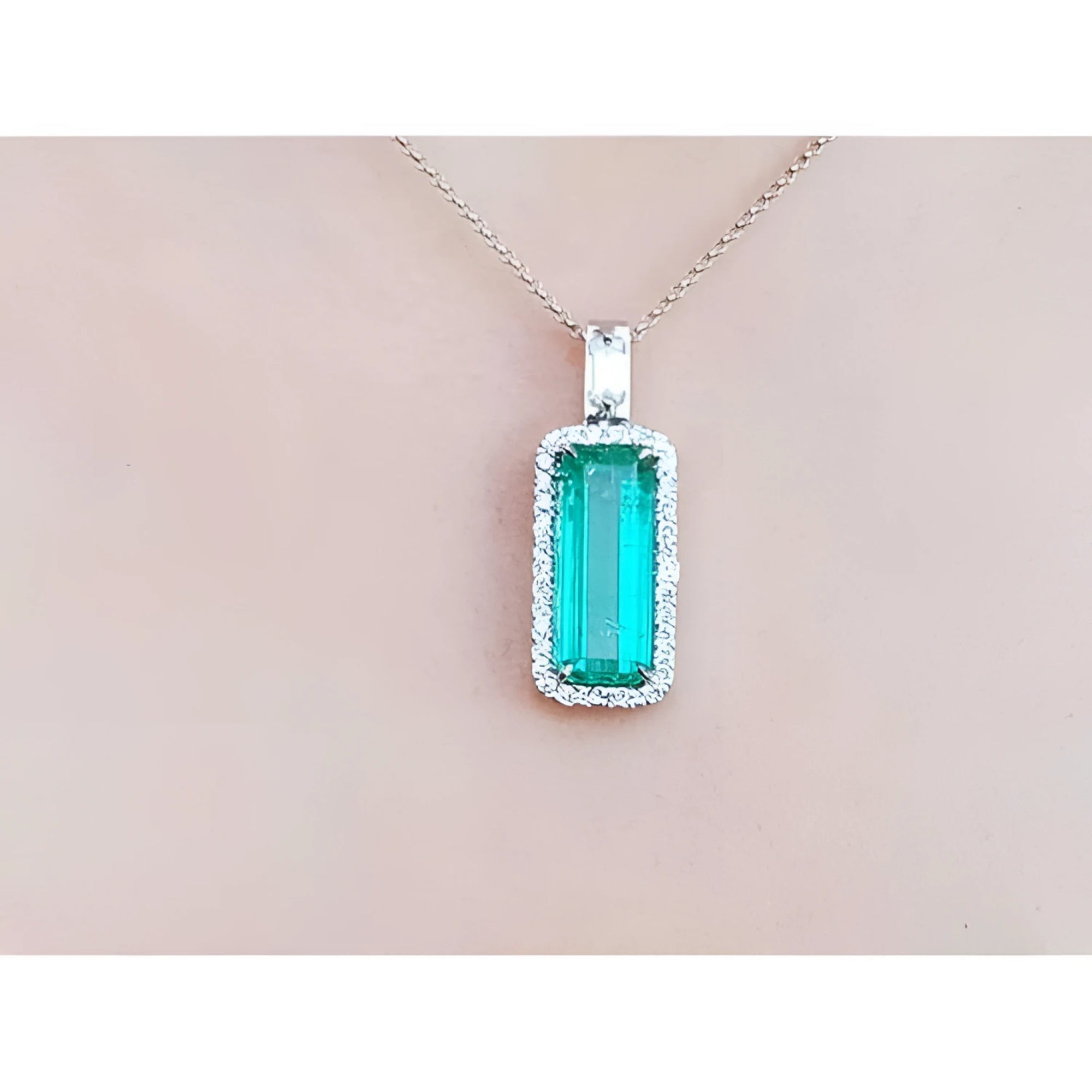 Green emerald pendant necklace on a light pink background