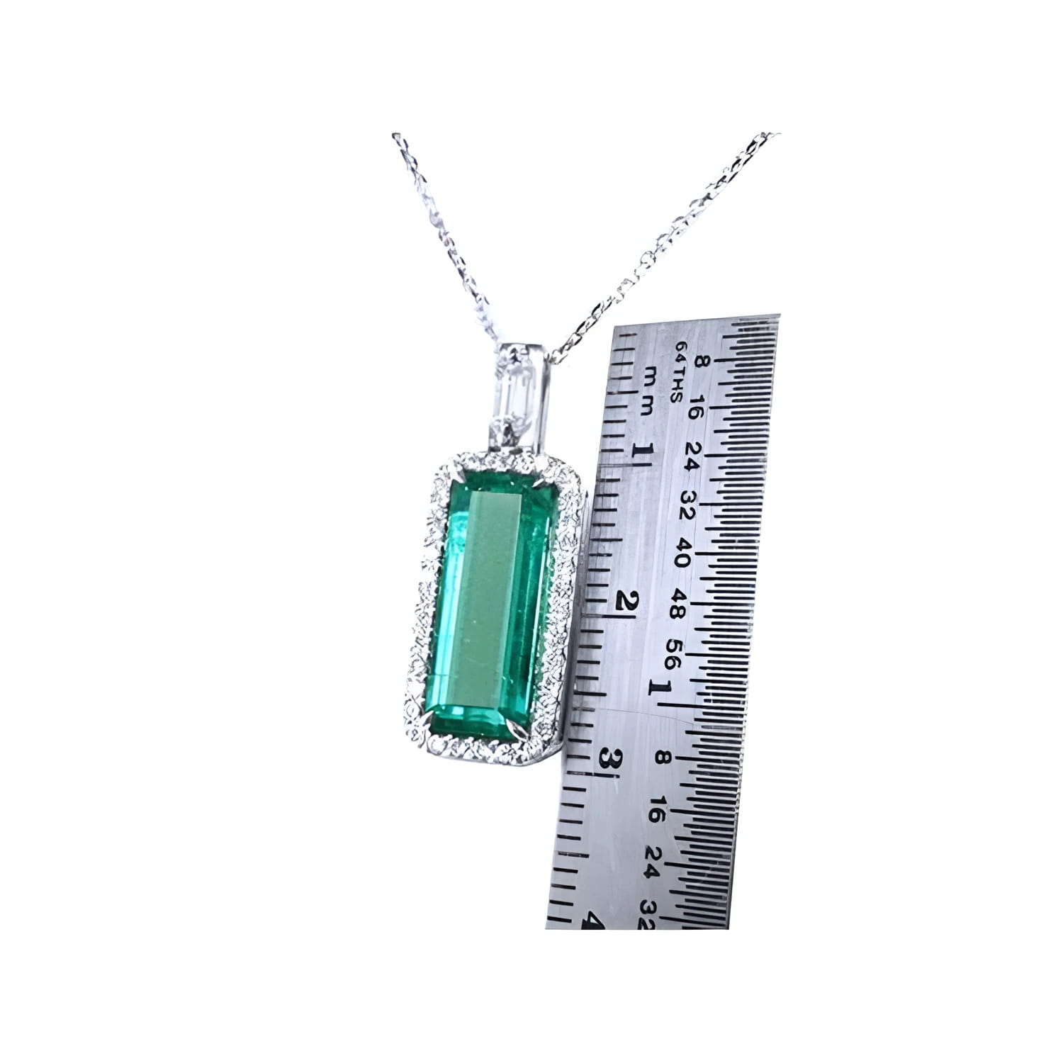 Elongated natural emerald pendant with halo diamonds in 18K white gold, shown next to a ruler.