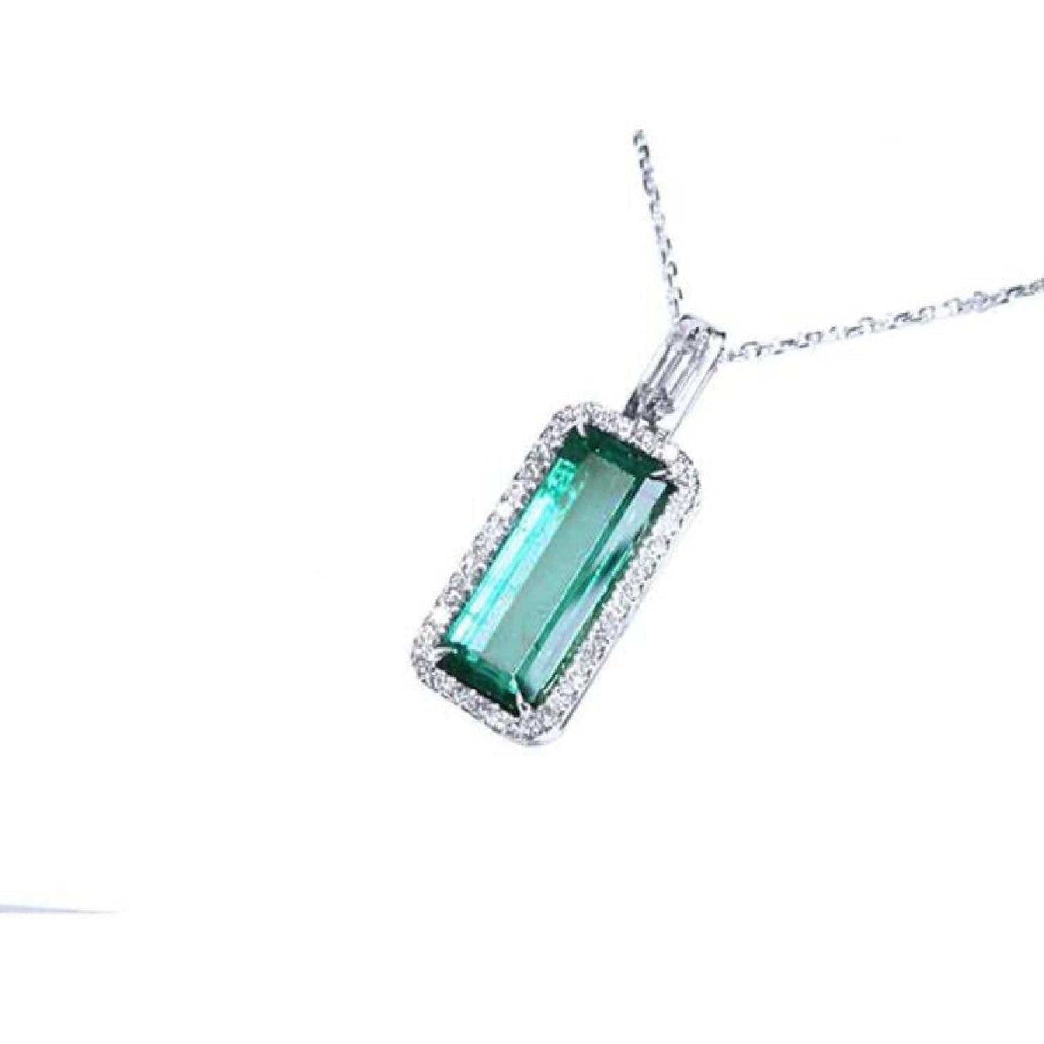 Elongated natural emerald pendant with halo diamonds in 18K white gold.