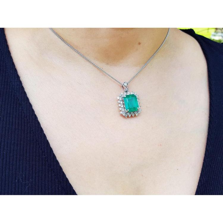 7.78 ct. natural emerald pendant with halo diamonds in 14K white gold, worn on a necklace.