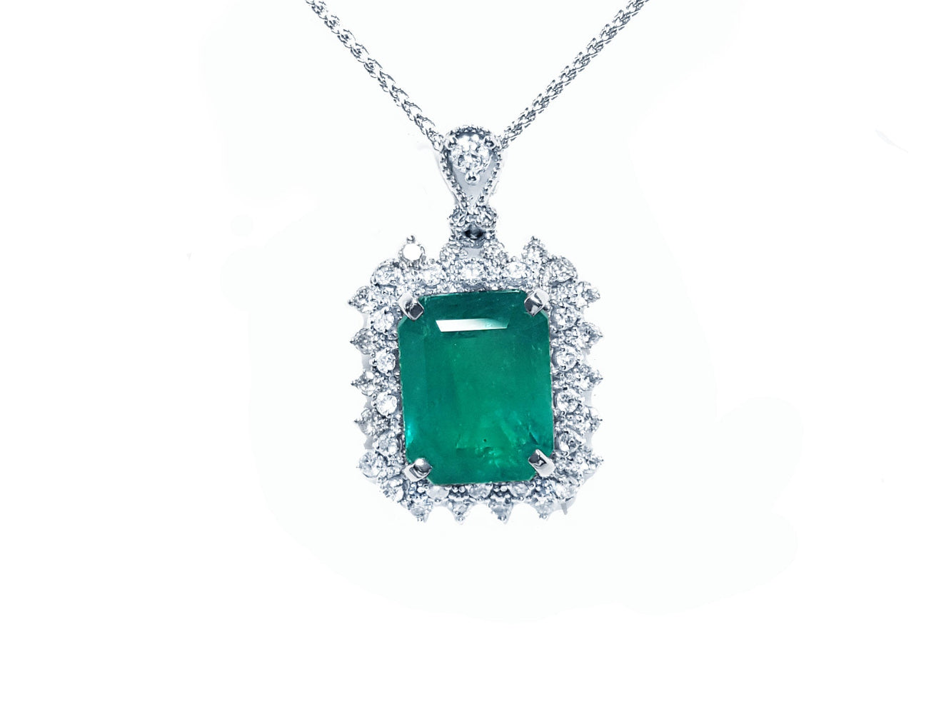 A Muzo mine emerald pendant necklace with a halo diamond on a white gold chain topside view
