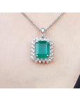 Emerald pendant necklace halo diamond on a white gold chain, skin background
