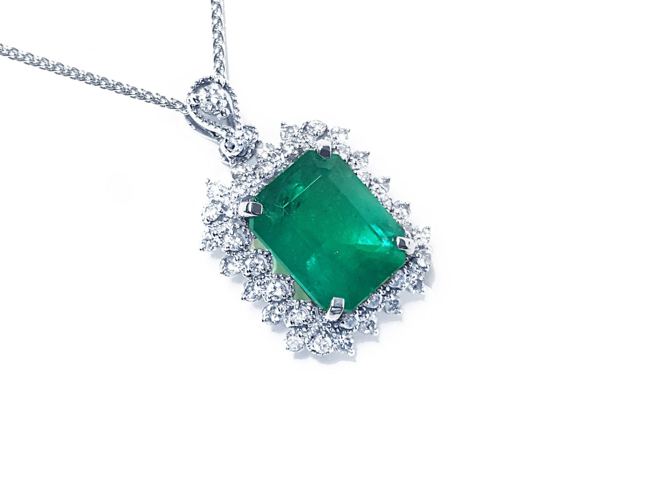A Colombian emerald pendant necklace with halo natural diamond in white gold topside view.
