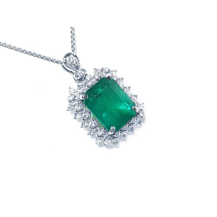 A Colombian emerald pendant necklace with halo natural diamond in white gold topside view.