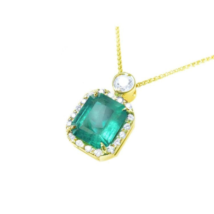 7.09 ct emerald pendant necklace with diamond halo and round diamond accent on 18K yellow gold chain.