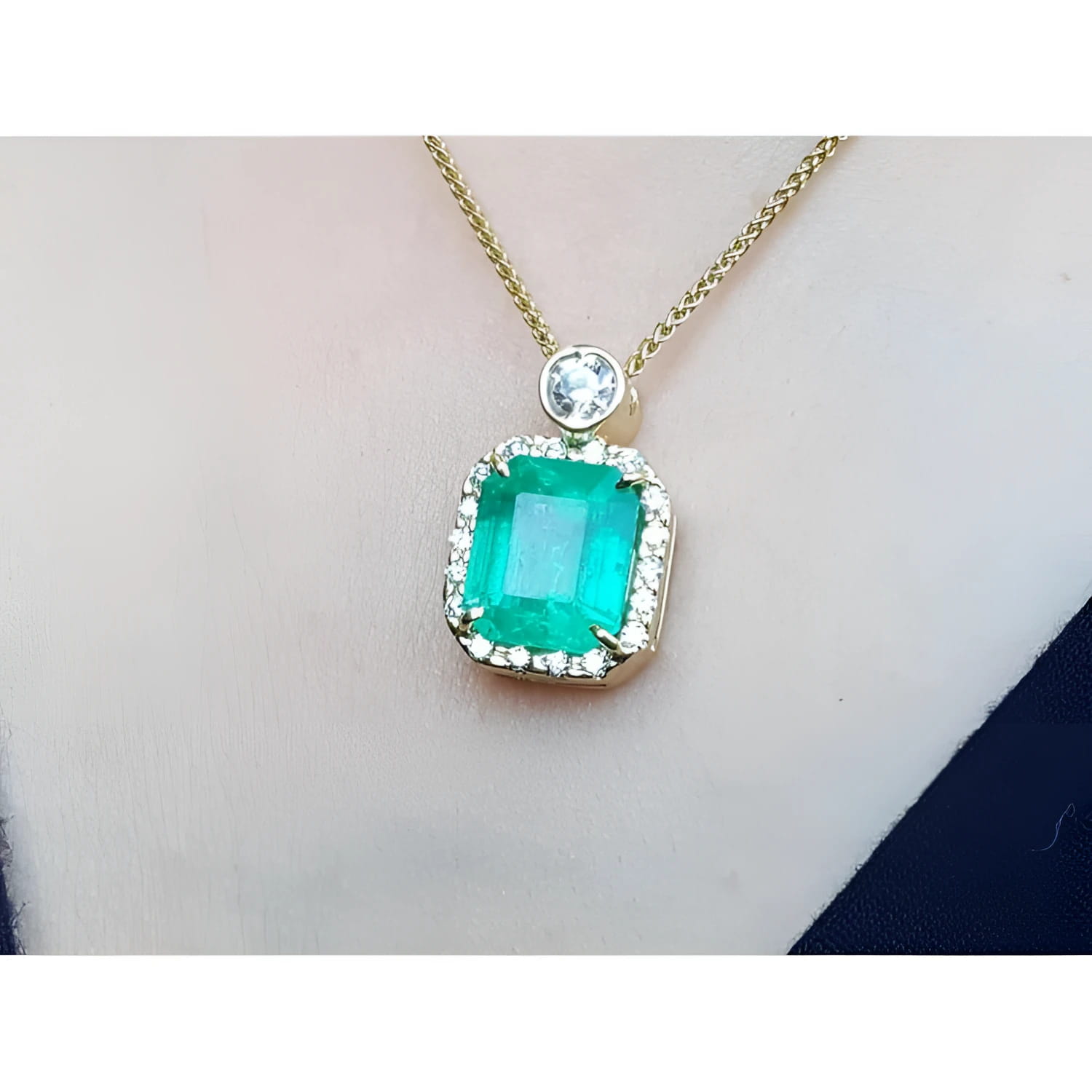 18K yellow gold necklace with a large emerald-cut emerald pendant surrounded by a halo of diamonds.