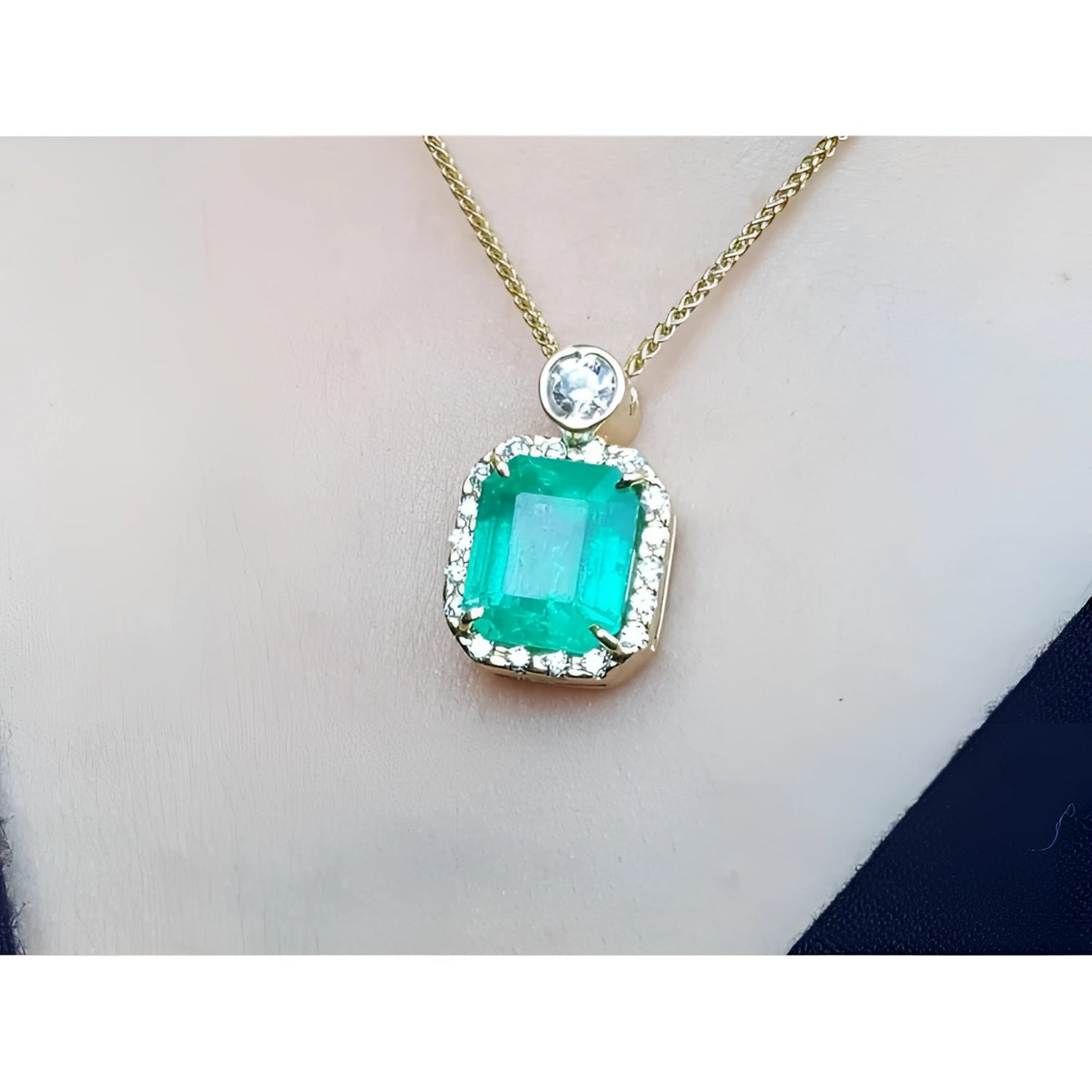 18K yellow gold necklace with a large emerald-cut emerald pendant surrounded by a halo of diamonds.