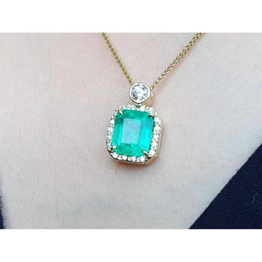 18K yellow gold necklace with a large emerald-cut emerald pendant surrounded by a halo of diamonds.