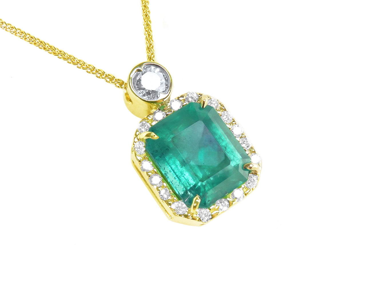 A 18k yellow gold pendant with a natural emerald and diamond accents on a topside view.