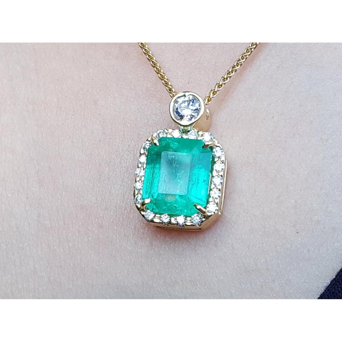 A square natural colombian emerald in a halo diamond pendant made in 18k yellow gold topside view.