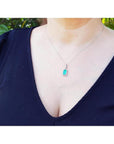Woman wearing a 1.70 ct. Muzo Colombian emerald pendant with a diamond halo in 18K white gold.