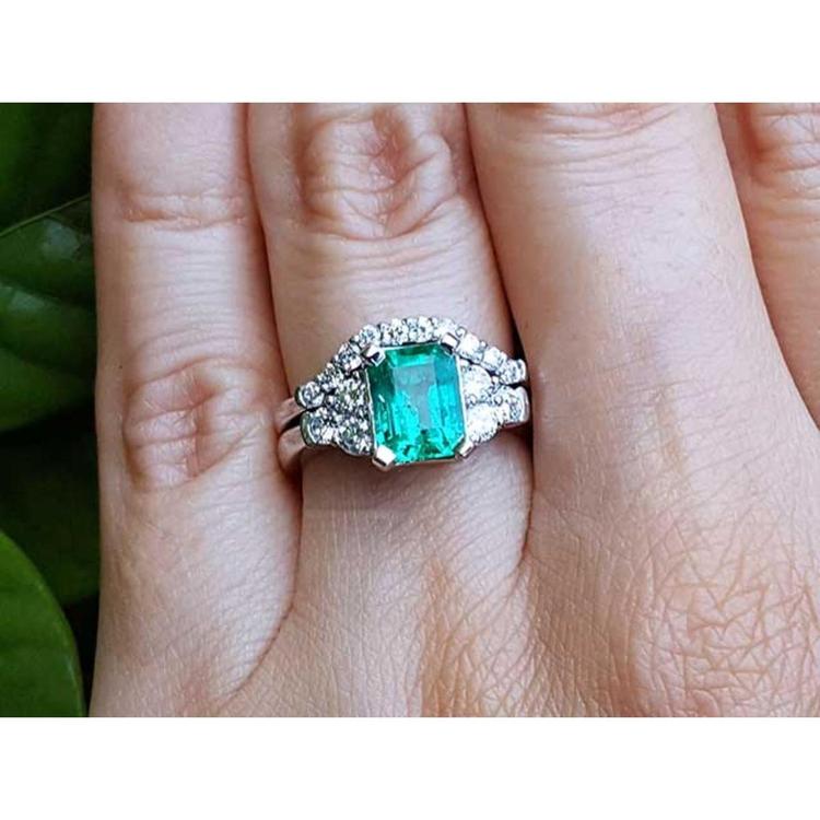 A real Colombian emerald and matching band ring with diamonds white gold on a finger.