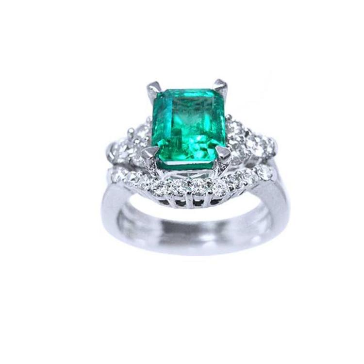 Emerald-cut vivid bluish green emerald ring with matching diamond band in white gold.