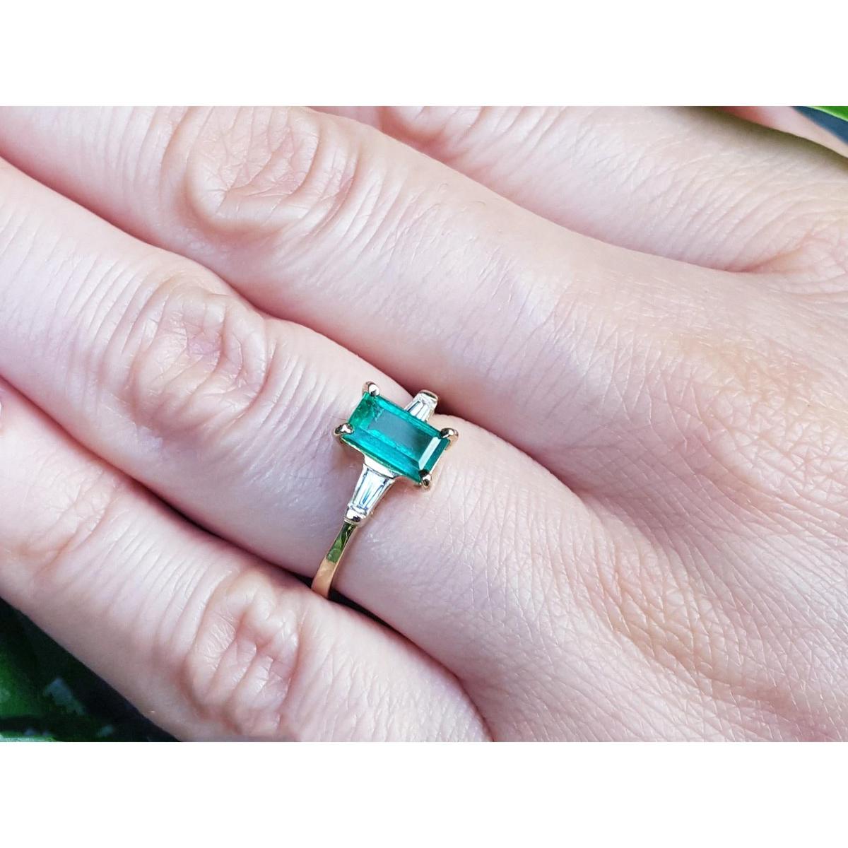 GA yellow gold ring with a real colombian emerald on a person's finger.