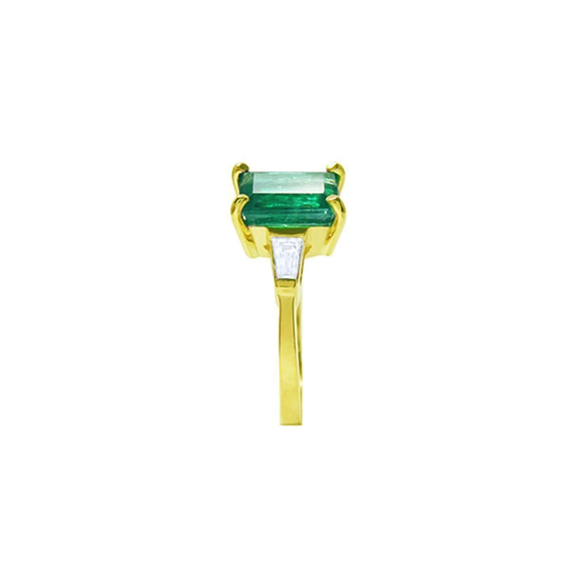 
the side profile of this colombian emerald ring shows the side top and band profile on a white background.