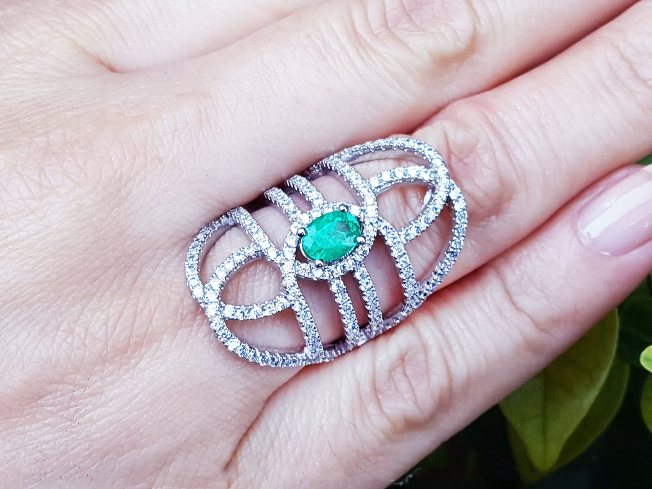 Silver ring with a Muzo born colombian emerald on a hand.