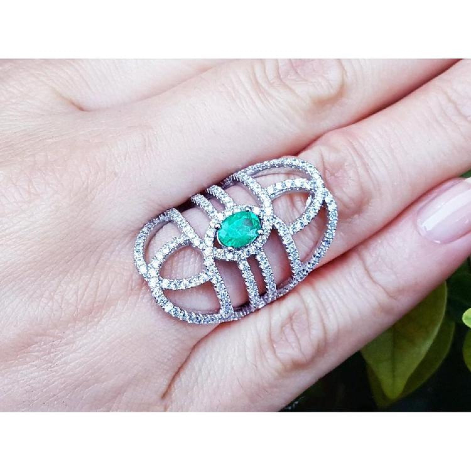 Sterling silver ring with a natural oval emerald center and CZ halo, featuring an intricate filigree design.