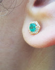 A close up of ear wearing a 14k gold emerald stud earring.