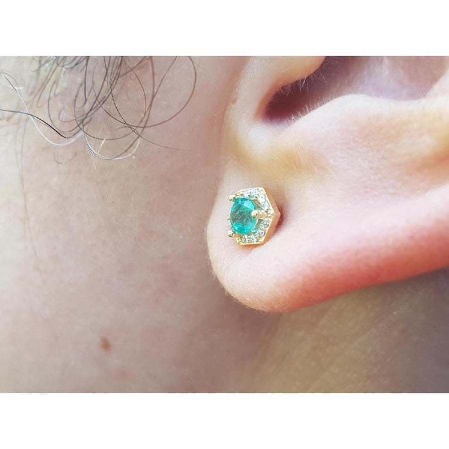 Hexagon emerald and diamond stud earring in 14K yellow gold on an ear.
