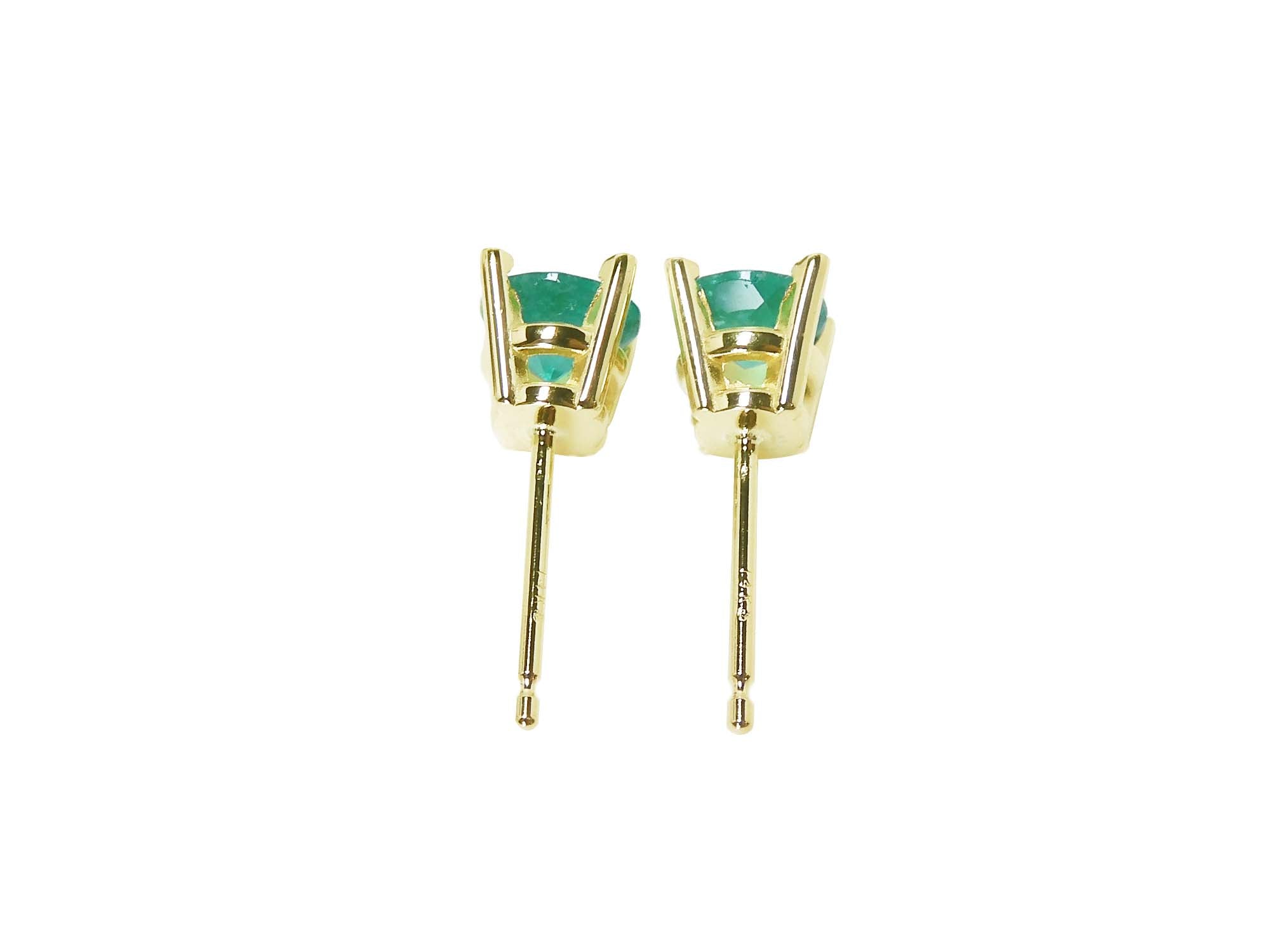 A pair of emerald stud earrings in 14k yellow gold, underside profile view.