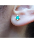 Girls' 0.32 ct. round natural Colombian emerald stud earring in 14K gold, worn on an ear.