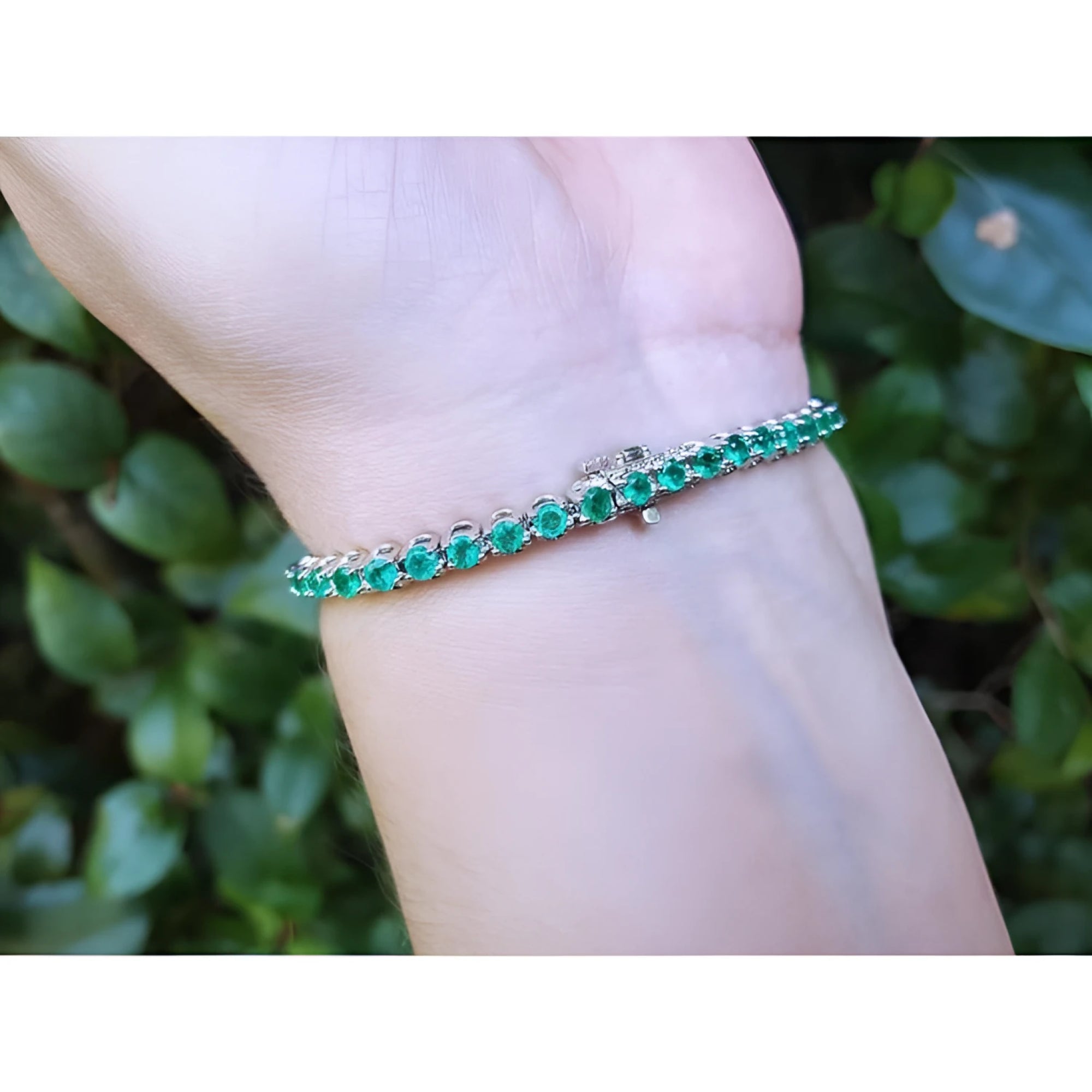 Colombian emerald tennis bracelet with round green emeralds in 14K white gold on a wrist.