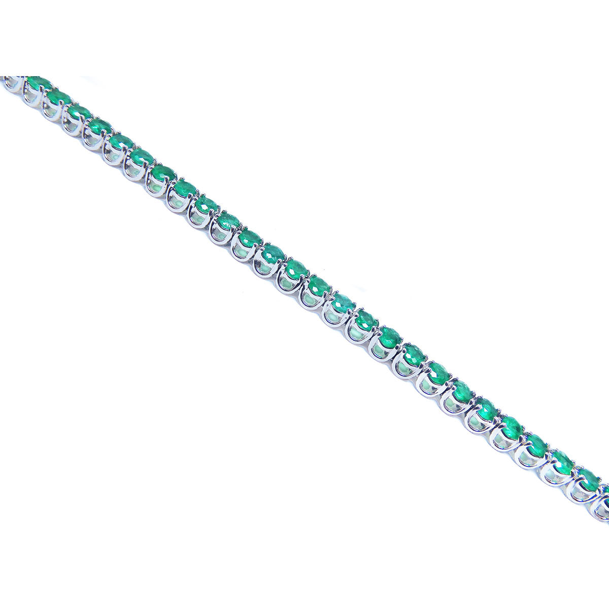 The side view of a white gold tennis bracelet with round cut emeralds on a white background.