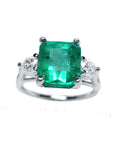The front side of this emerald three stone ring shows the top side with side diamonds profile.