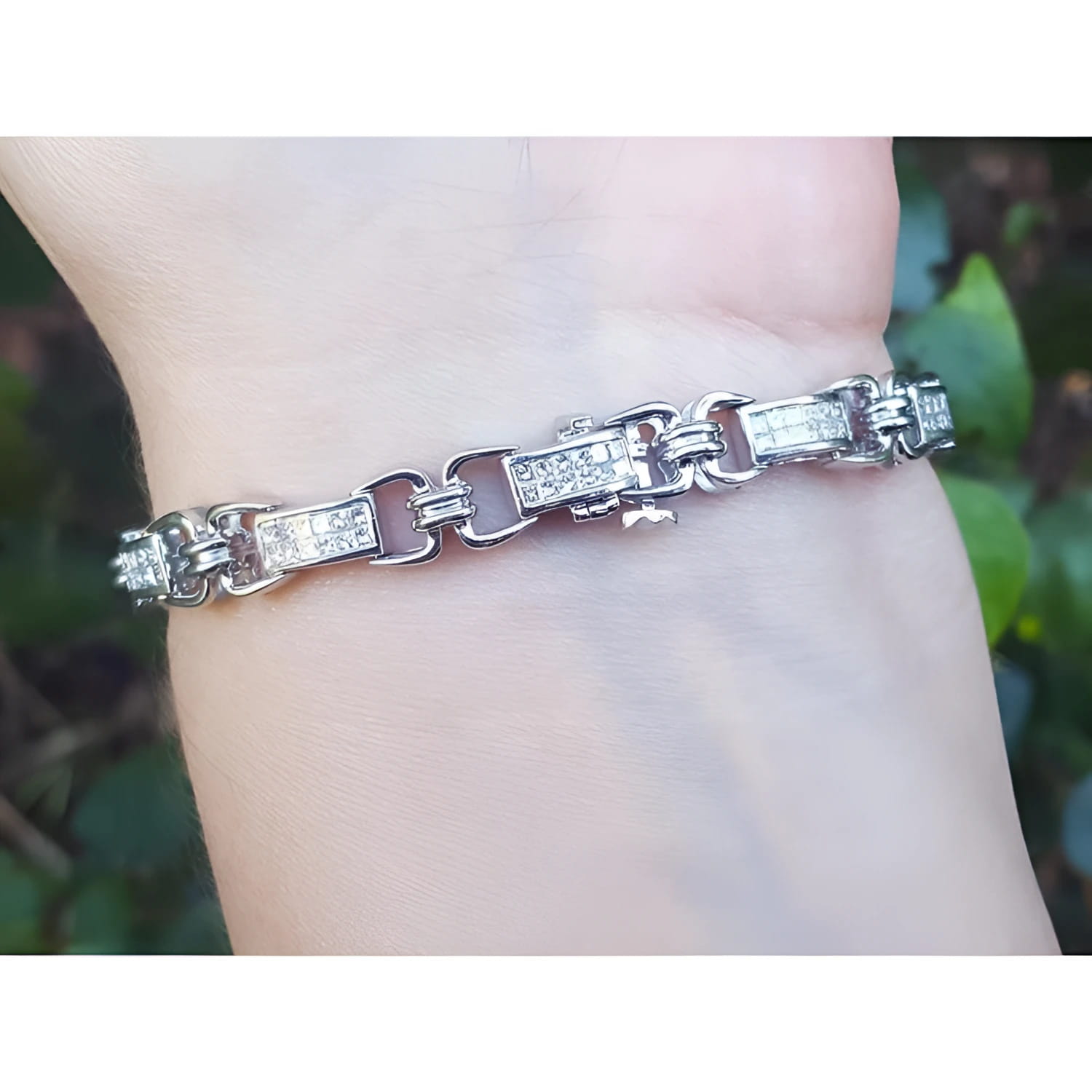 Silver bracelet with princess cut diamonds, worn on a wrist.