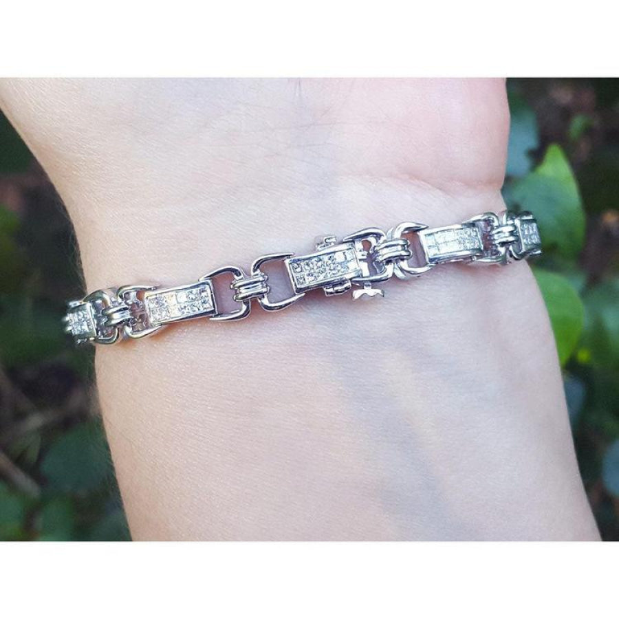 White gold bracelet with princess cut diamonds, worn on a wrist.