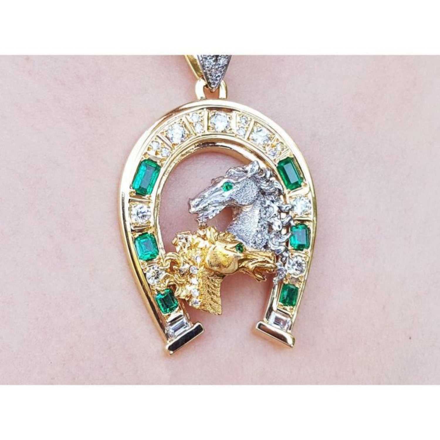 18K yellow gold horseshoe pendant with emeralds, diamonds, and two horse heads.