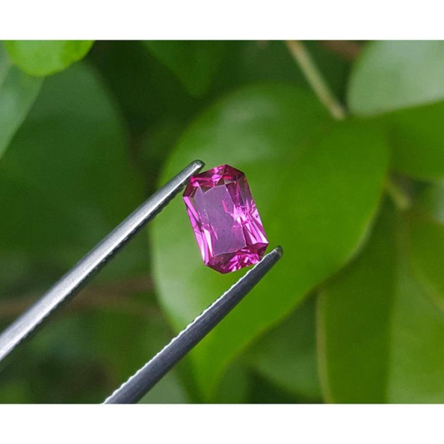 1.38 ct GIA certified loose natural purplish pink sapphire, fancy emerald-cut, held by tweezers.