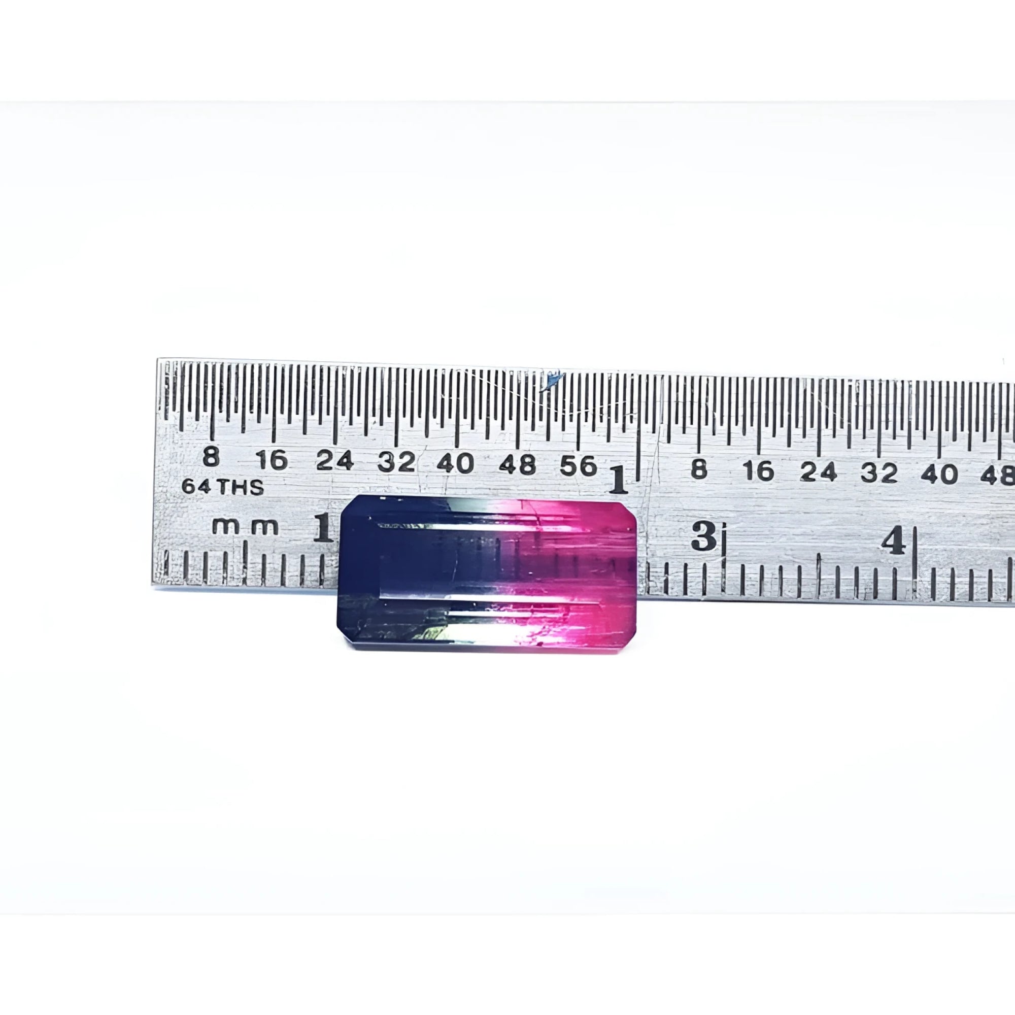 Emerald cut 6.11 ct natural loose watermelon tourmaline with bluish green and red-orange hues, measured against a ruler.