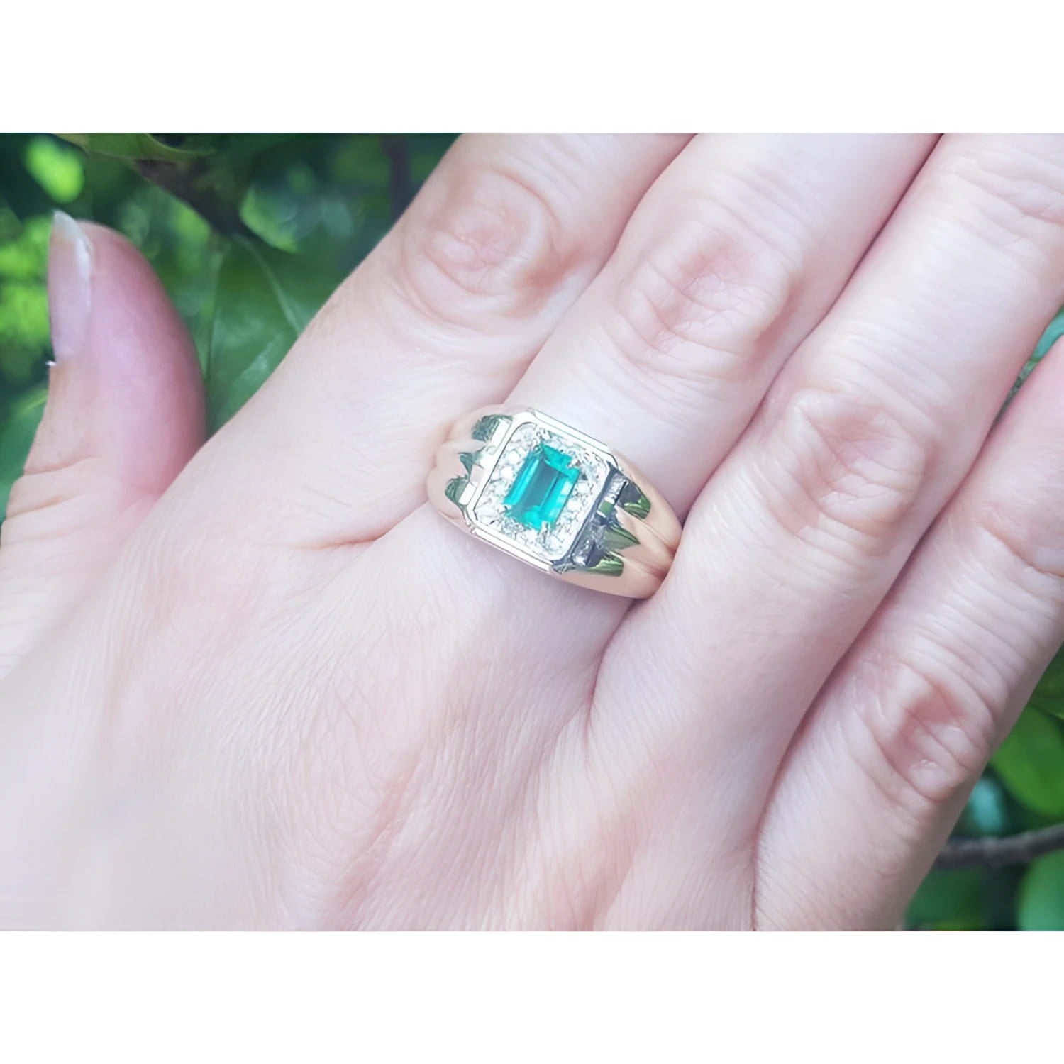 Men's 14K yellow gold ring with a rectangular Muzo emerald and diamond halo, worn on a hand.
