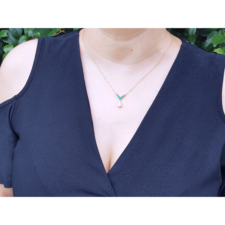 Mother&#39;s Day gift diamond necklace dangling from a V style center piece with natural round cut emeralds prong set in 14k yellow gold